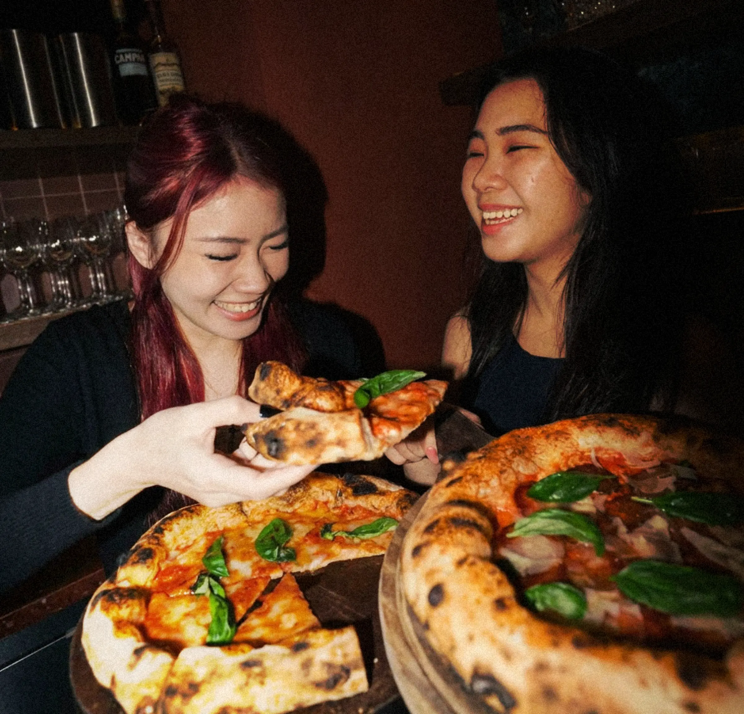 Two guests laughing over pizza at Casa Vostra