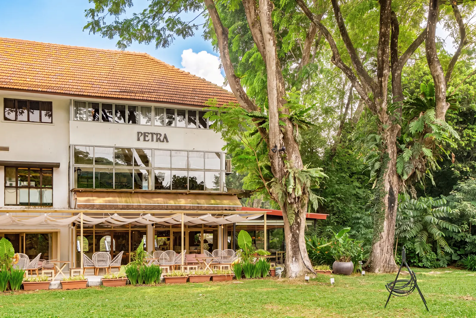 The whitewashed two-storey Petra building in Dempsey, with a terracotta roof, terrace and tropical trees